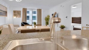 A modern kitchen with a stainless steel sink, a sleek faucet, and a dining area with a table and chairs. - The Club 1606 · Impressive Unit in the heart of Brickell W Parking (Miami)