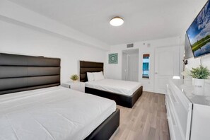 Ett modernt hotellrum med två sängar, en platt-TV, en liten balkong och utsikt över omgivningarna.