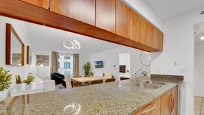 A modern kitchen with granite countertops, wooden cabinets, and a built-in dishwasher. - The Club 1606 · Impressive Unit in the heart of Brickell W Parking (Miami)