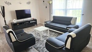 Ein Wohnzimmer mit einem schwarz-weißen Sofa, einem Flachbildfernseher, einem Couchtisch und einer schwarzen Unterhaltungsanlage.
