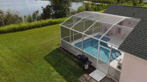 Ein überdachter Pool mit Glasveranda, Grill und Terrassenbereich.