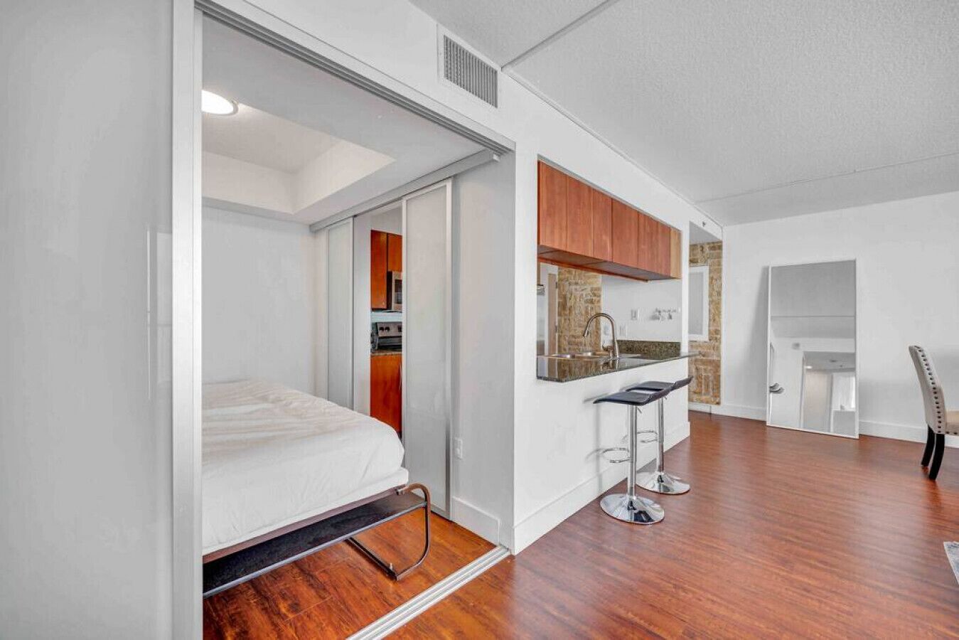A compact room with a bed, a kitchenette, and a small bar area.