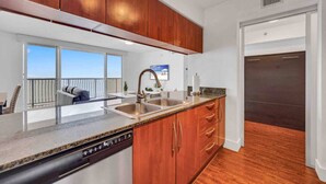 A modern kitchen with wooden cabinets, a stainless steel sink, and a dishwasher. - The Club 1601 · Ocean View Amazing Unit Brickell (Miami)