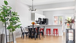 A modern kitchen with white cabinets, a black refrigerator, and a dining area with black and red chairs. - Little 5 Condo: King Beds | Ping-Pong | Garage (Bloomington)