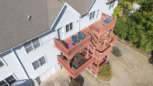 A multi-story building with a red balcony structure, a covered patio area, and a small garden space. - Little 5 Condo: King Beds | Ping-Pong | Garage (Bloomington)