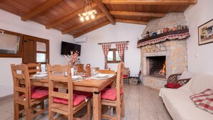 A dining area with a stone fireplace, wooden furniture, and a television on the wall. - Amazing home in Jadreski with private swimming pool, can be inside or outside (Jadreski)