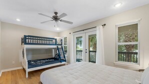 A bedroom with a bunk bed, a single bed, a ceiling fan, and a window with blinds.