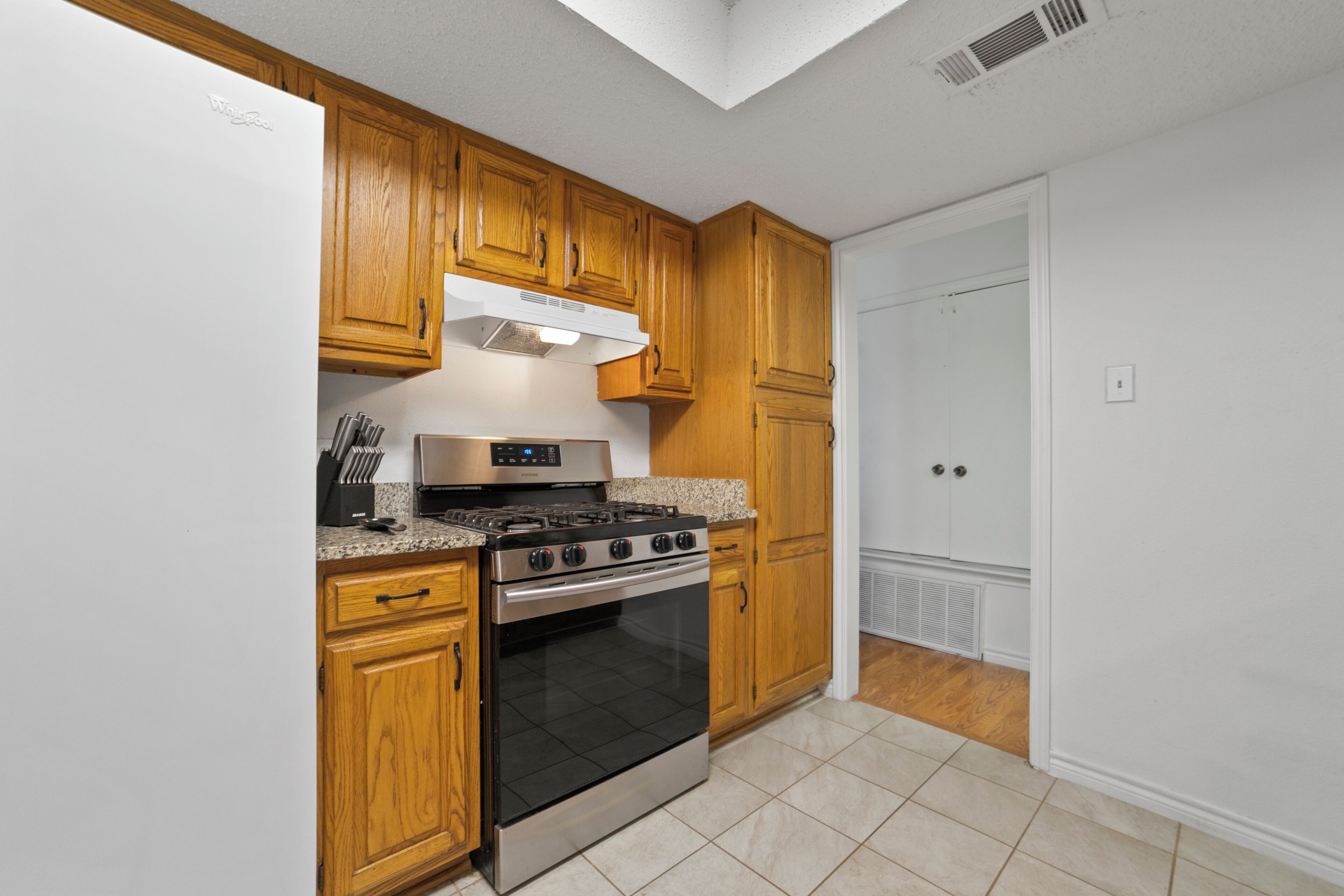 A kitchen with wooden cabinets, a stainless steel stove, and a white refrigerator.