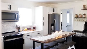 Eine moderne Küche mit weißen Schränken, einer Edelstahl-Mikrowelle, einem eingebauten Backofen und einem Essbereich mit einem Holztisch und Bänken.