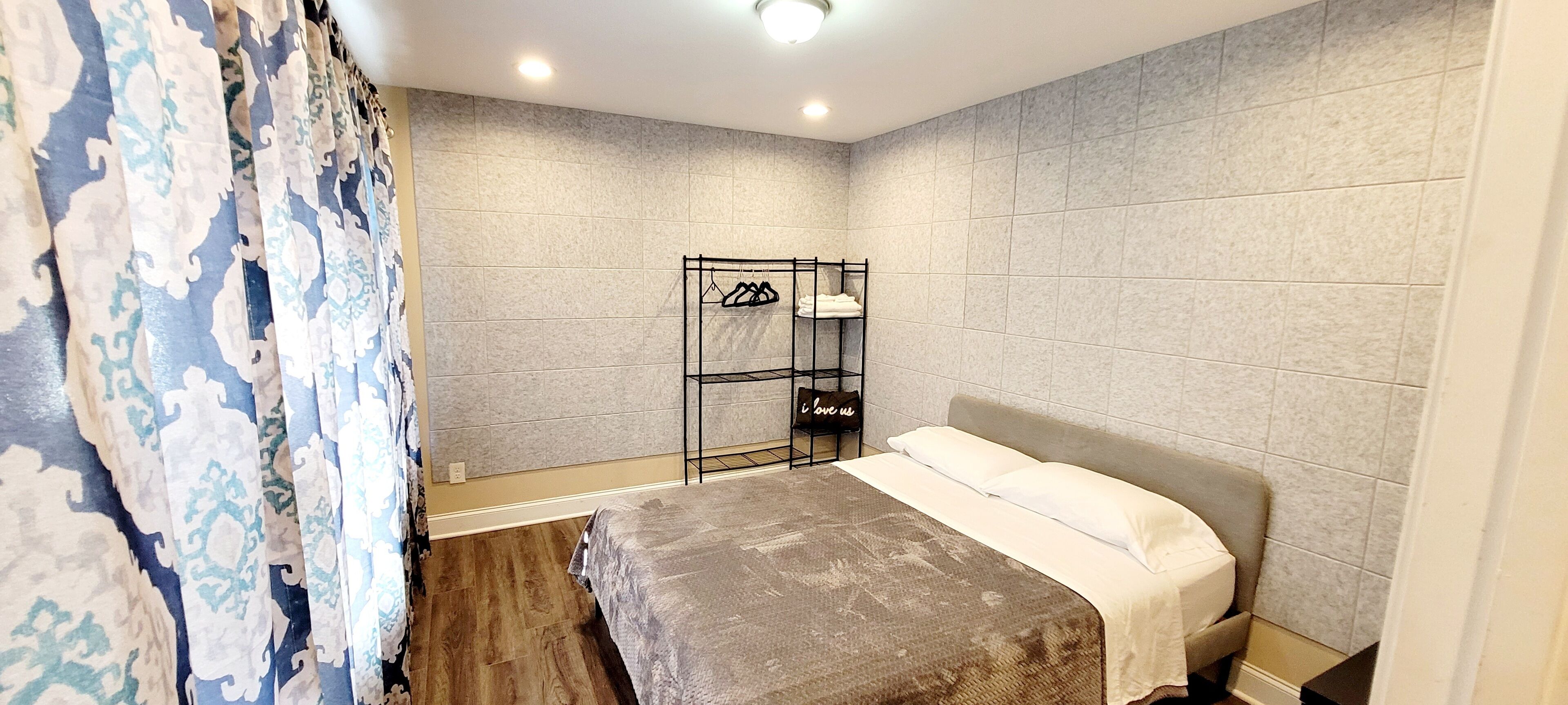 Une chambre à coucher avec un lit, une armoire et une étagère où sont suspendus des vêtements.