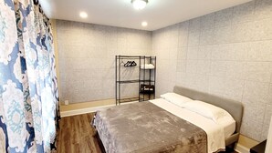 Een slaapkamer met een bed, een kledingkast en een plank met hangende kleding.
