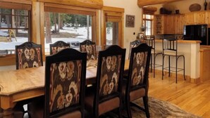 A dining area with a wooden table and chairs, a kitchen with wooden cabinets, and a view of the outdoors. - Amazing Mountain Home in Blue River-7 minutes from Breckenridge! (Blue River)