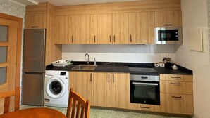 A compact kitchen with wooden cabinets, a stainless steel refrigerator, a microwave, a washing machine, and an oven. - Fantástico Retiro Rural en el Corazón de Euskadi (Elgoibar)