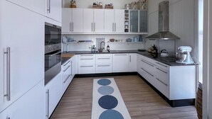 A modern kitchen with white cabinets, stainless steel appliances, and a wooden floor. - Amazing home in Lyngdal with WiFi (Lyngdal)