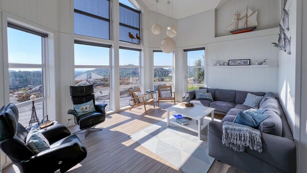 A spacious living room with large windows, a gray sofa, a coffee table, and a view of the outdoors. - Amazing home in Lyngdal with WiFi (Lyngdal)