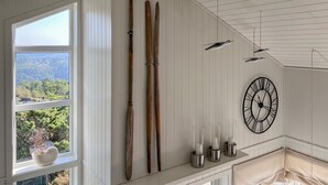 A room with a large window, wooden skis, a wall-mounted clock, and a shelf with glass candle holders. - Amazing home in Lyngdal with WiFi (Lyngdal)