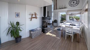 A spacious, well-lit room with a wooden floor, a dining table set for four, and a large window offering a view of the outdoors. - Amazing home in Lyngdal with WiFi (Lyngdal)