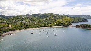 A coastal area with boats on the water, a beach, and a densely forested hillside. - Eclectic Studio with Bold Taste (Ocotal)