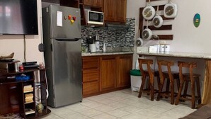 Une cuisine dotée de meubles en bois, d’un réfrigérateur, d’un four à micro-ondes et d’un coin repas avec des chaises.