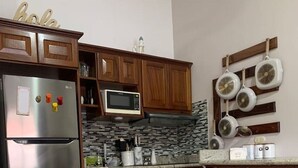 Une cuisine avec des meubles en bois, un réfrigérateur en acier inoxydable, un four à micro-ondes, un pare-feu en carreaux et un porte-ustensiles.