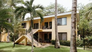 A two-story building with a staircase leading to a balcony, surrounded by palm trees and a well-maintained lawn. - Dolce Vita La Colina in Ocotal (Ocotal)
