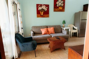 Un salon comprenant un canapé, un fauteuil, une table basse et des œuvres d’art accrochées au mur.