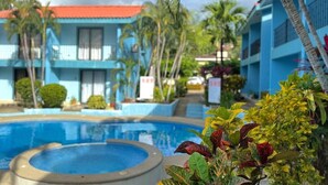 A swimming pool surrounded by tropical plants and buildings with blue exteriors. - Villa Riviera Walk to Beach Condo Playas del Coco (Del Coco Beach)