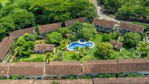 Ein Resort mit mehreren bungalowartigen Gebäuden, einem zentralen Schwimmbad und üppiger Vegetation.