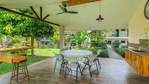 A covered outdoor area with a round table and chairs, a wooden bench, a ceiling fan, and a clock on the wall. - Lovely Studio in Playa Ocotal (Playa Ocotal)