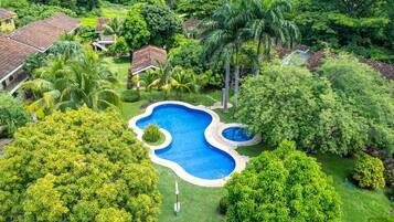 An aerial view of a residential area with a swimming pool surrounded by lush greenery and houses.