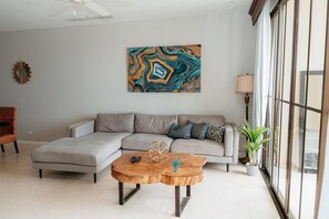 A modern living room with a sectional sofa, a wooden coffee table, and a large abstract painting.