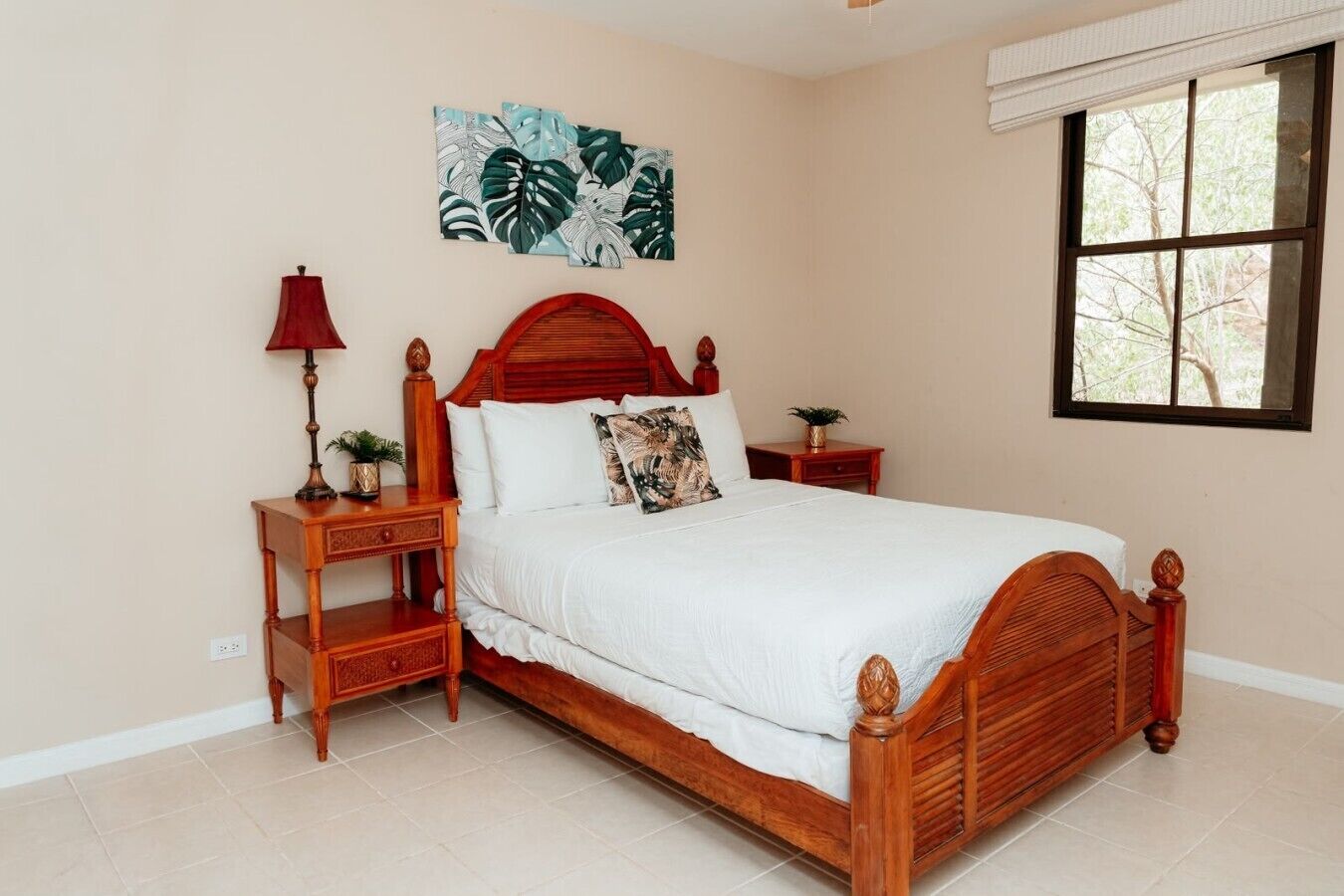 A bedroom with a wooden bed, a nightstand, a lamp, a wall art piece, and a window.