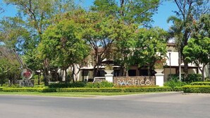 A building with a sign reading 'PACIFICO' surrounded by trees and a clear sky. - Lovely 2 bdrm Condo in Pacifico (Coco)
