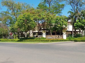 A building with a sign reading 'PACIFICO' surrounded by trees and a clear sky. - Lovely 2 bdrm Condo in Pacifico (Coco)
