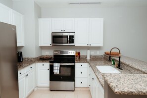 A modern kitchen with white cabinets, a stainless steel oven, a microwave, and granite countertops.