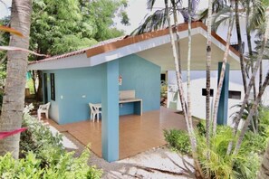 A small building with a blue exterior, a covered patio area, and a white chair.