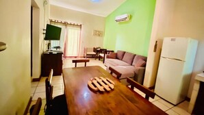 A dining area with a wooden table, chairs, a sofa, and a refrigerator. - 2bdrm/2bth walk to the beach1 (Coco)
