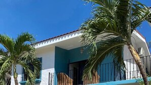 A two-story building with a balcony, surrounded by palm trees and cacti. - 2bdrm/2bth walk to the beach1 (Coco)