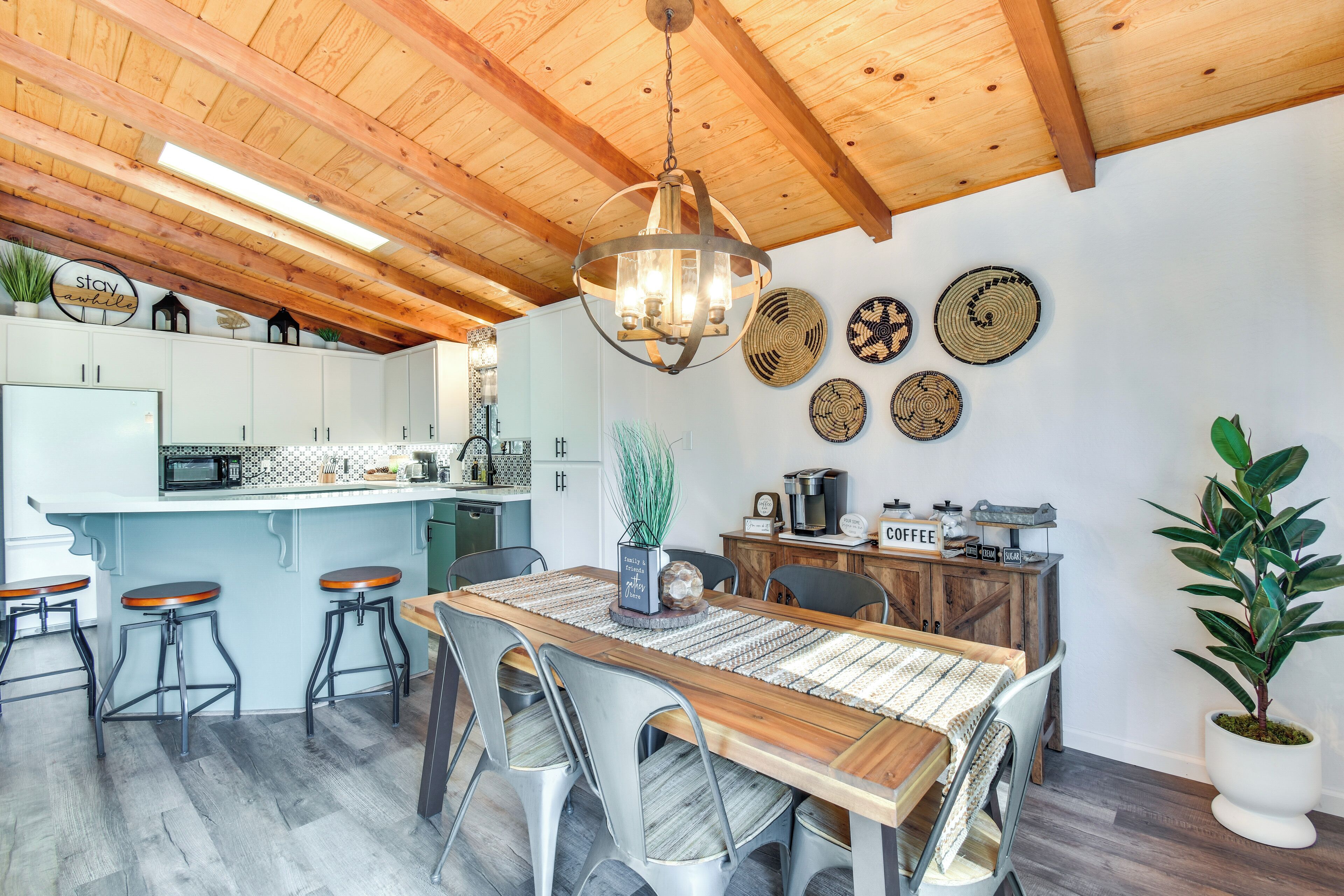 Une cuisine moderne avec un plafond en bois, un îlot central doté de tabourets et des éléments décoratifs fixés au mur.
