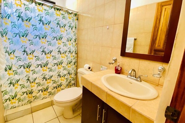 Un baño con inodoro, lavamanos y cortina de ducha.