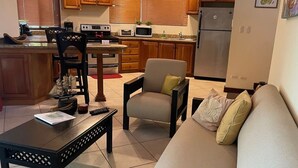 A living room with a sofa, a coffee table, and a dining area with a chair and a ship model. - Ocean view and Private Pool in Playa Hermosa (Playa Hermosa)