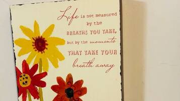 Une carte décorative à accrocher au mur, ornée d’une citation sur la vie et le souffle, et accompagnée de trois fleurs stylisées.
