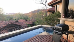 A swimming pool with a wooden deck, a barbecue grill, and a view of houses and hills. - Ocean view and Private Pool in Playa Hermosa (Playa Hermosa)