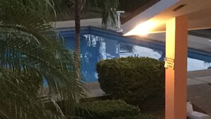 Ein Poolbereich mit Palme und Hecke.