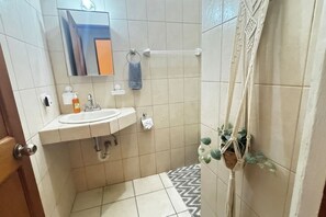 Une petite salle de bain avec un lavabo, un miroir, un porte-serviettes et une plante en pot.