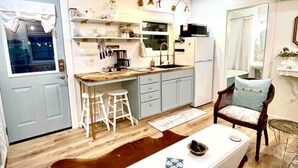 A compact kitchen with a dining area, a white sofa, and a red rug.