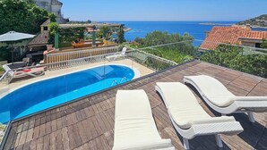 A rooftop pool with lounge chairs and a view of the sea.