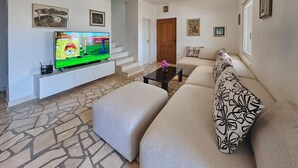 A living room with a sofa, a coffee table, a TV, and a staircase.