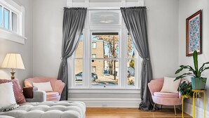 A living room with a large window, two sofas, a coffee table, a lamp, and a potted plant. - Cozy Victorian | King Bed, Private Yard, Walk to SoBo Restaurants (Denver)