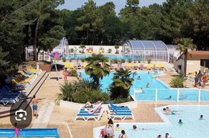Un área de piscina con varias piscinas, sillas de descanso y sombrillas.